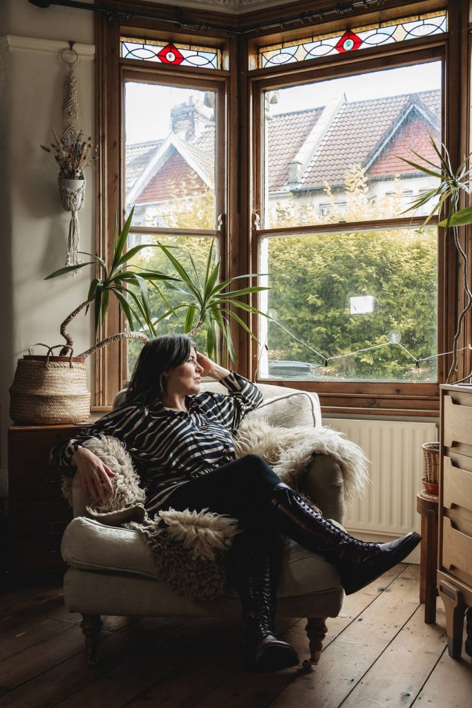 Wide shot of woman sitting gazing out the window, symbolising personal growth and moving forward with confidence.