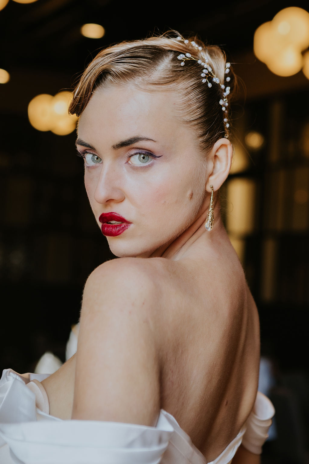 Model with fresh, glowing skin, bold red lipstick, and defined winged eyeliner in a modern bridal beauty look