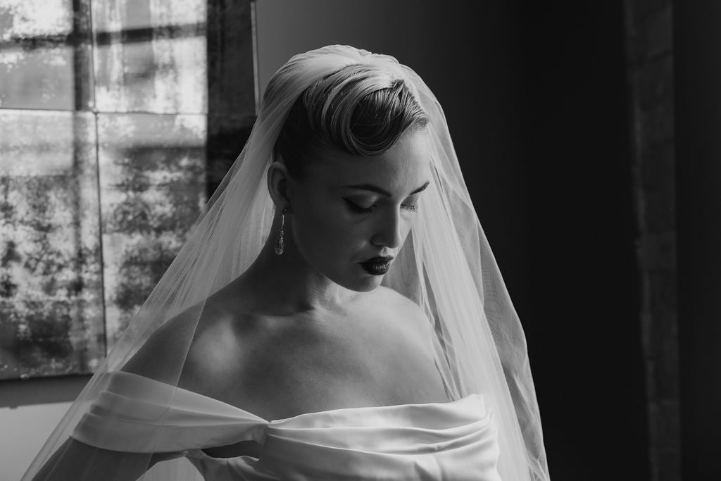 Black and white portrait of bridal model with smooth hair and flowing fabric, styled with an art deco twist and soft, elegant lighting